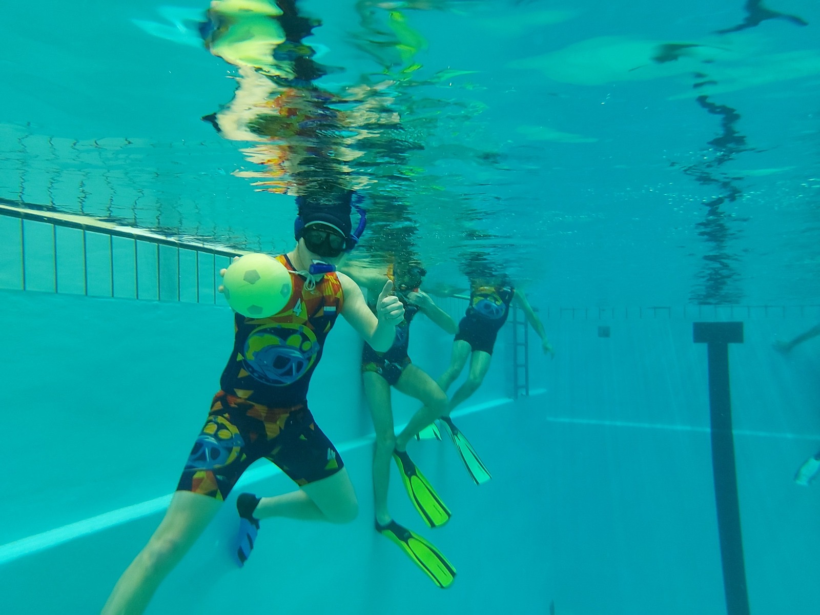 Onderwaterrugbyspeler met de bal onder water, met duimpje omhoog